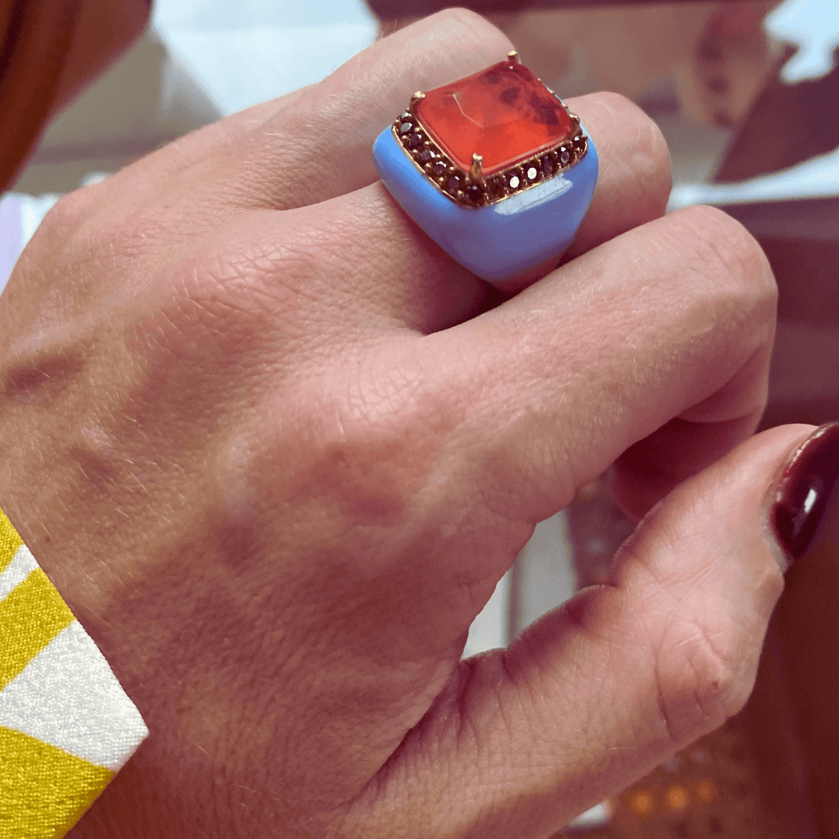 LAURIEN statement ring, light blue enamel band with orange-red center stone, worn on hand. GIADAN for Le.Paul Jewelgarden