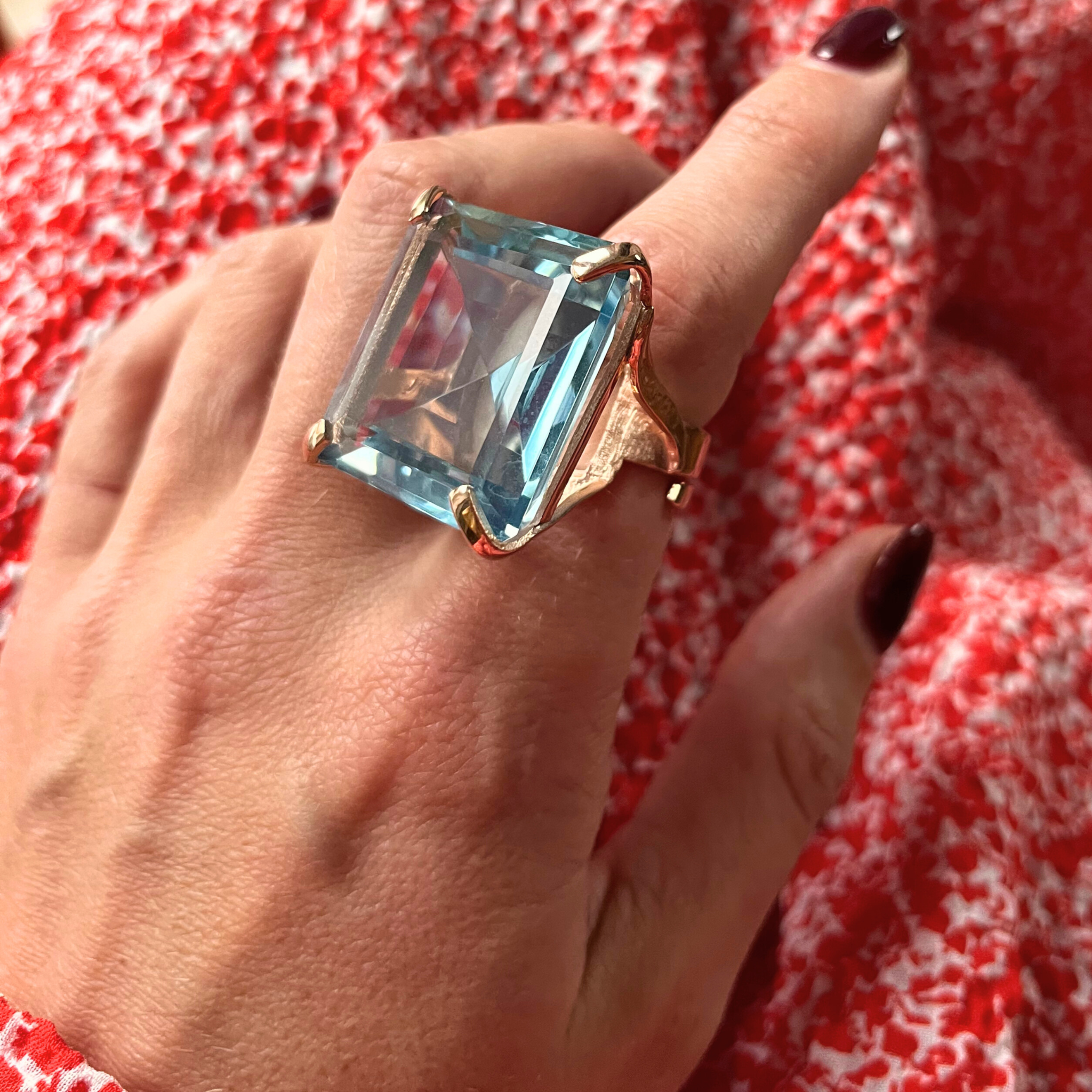 A hand wearing a rose gold plated band ring with a large light aquamarine blue zirconia stone -  NARCISA AQUA by Gadan for Le.Paul Jewelgarden